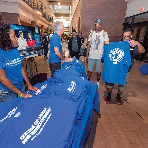 College of Media and Entertainment Celebration in the lobby of the Mass Communications Building, celebrating the college name change with free t-shirts, popcorn, and ice cream.